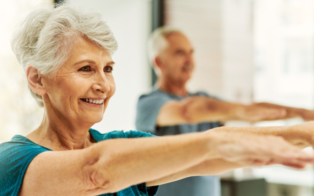 Two older adults stretch their arms during an exercise class