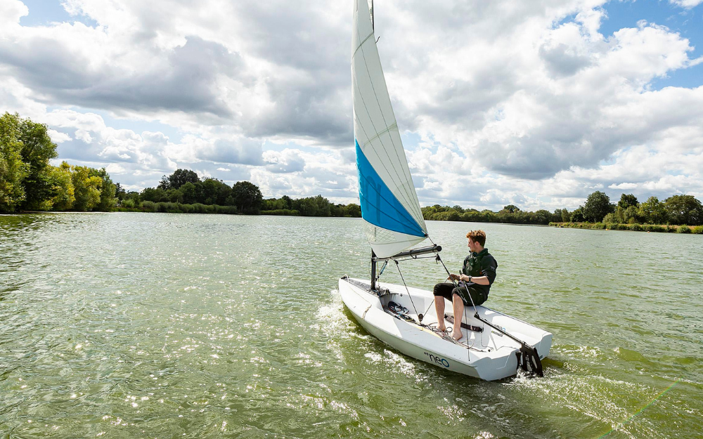 A boy uses a sailing boat on the lake at Dinton Pastures