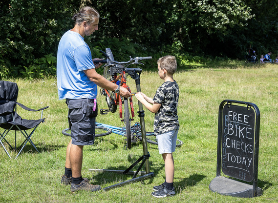 a man with a bike on a stand shows a young boy how to repair it