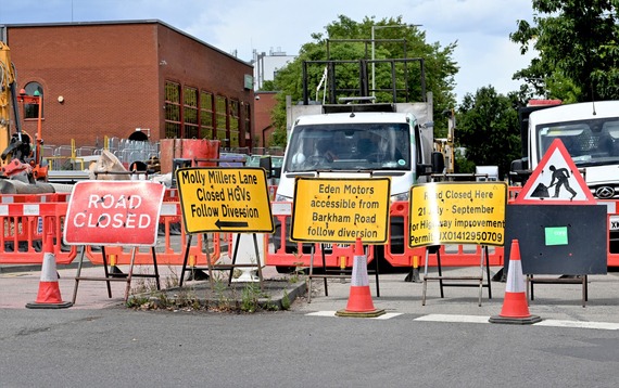 a series of closure and diversion signs at a busy roundabout on Molly Millars Lane, with construction vehicles behind them