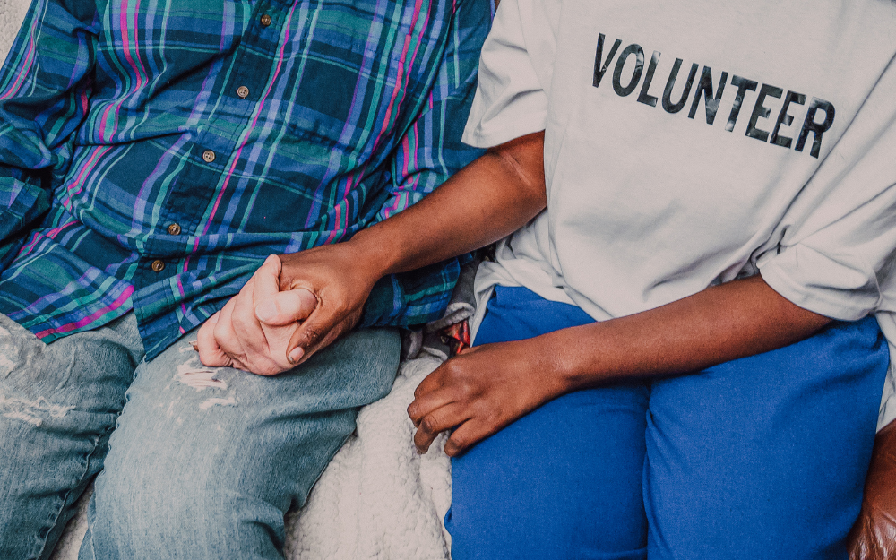 young volunteer holding older person's hand