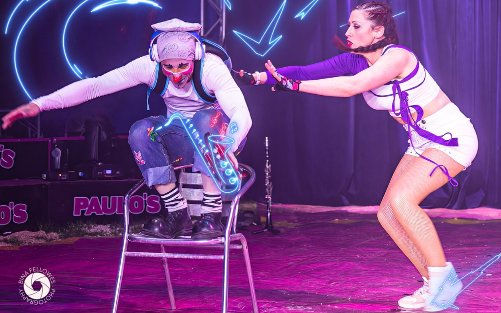 Two circus performers jump in the air with expressive faces