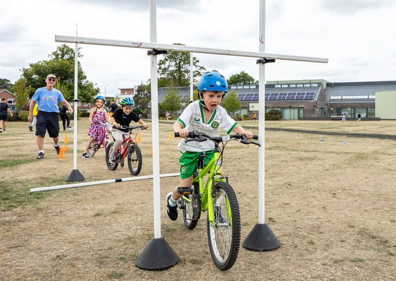 Children having a go on bike limbo cycling under bars