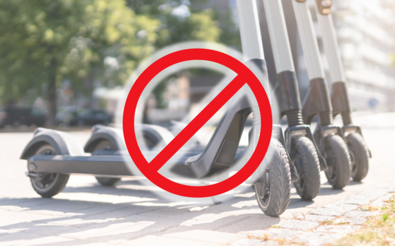 a line of electric scooters in the street with a red line through them, indicating that they are banned