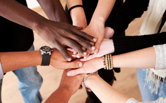 Hands stacked together in a circle in a moment of teamwork celebration