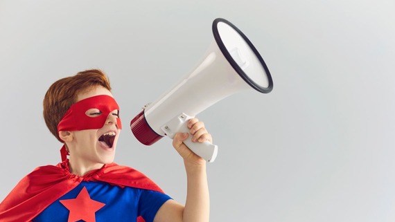 Boy dressed as superhero shouting into a megaphone