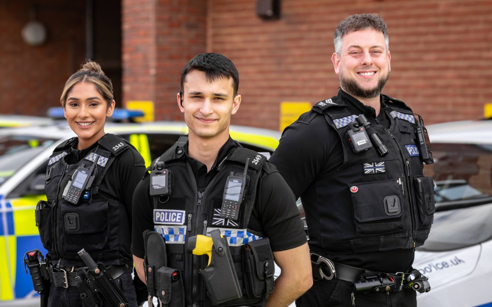 Police officers stood next to a police car