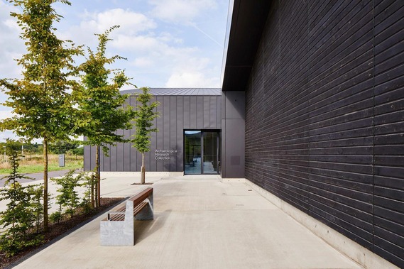 The British Museum centre, a black, modern barn-like building with a plate glass door and a smart avenue of trees leading to the entrance