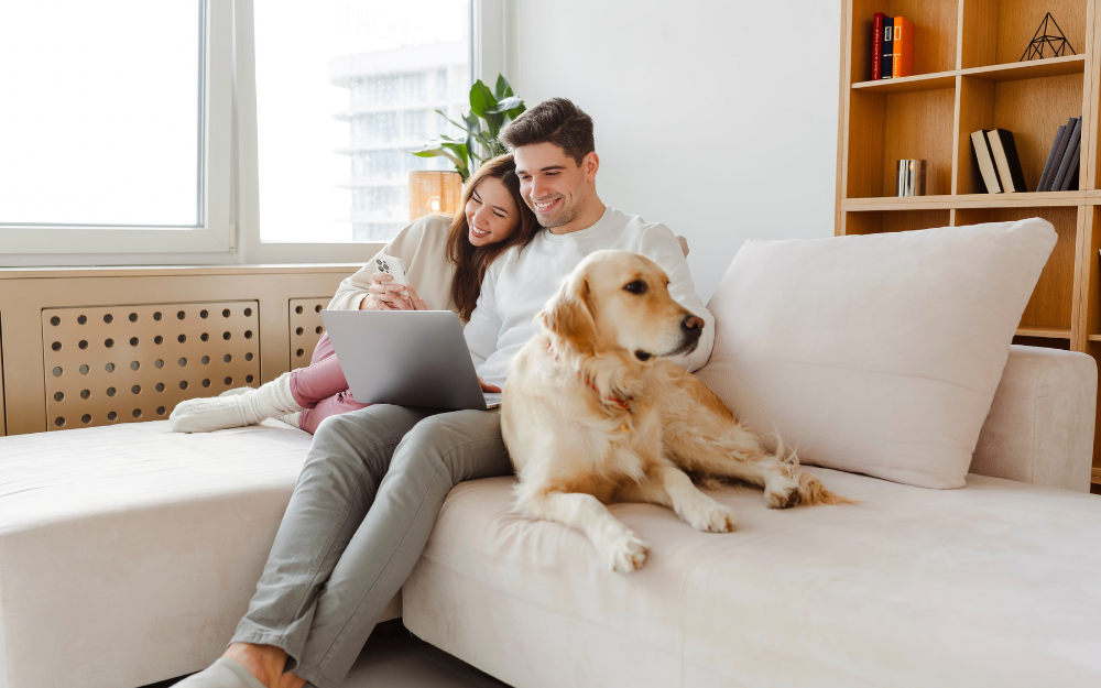 A couple with their dog snuggled on a sofa