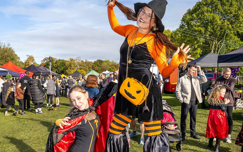 Two people in pumpkin outfits at a Halloween fair