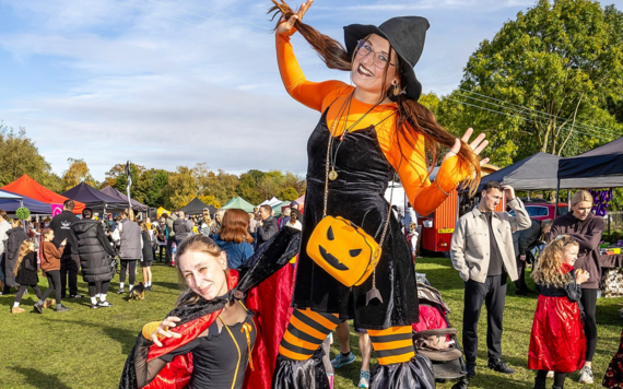 Woman dressed as a pumpkin on stilts at a fair