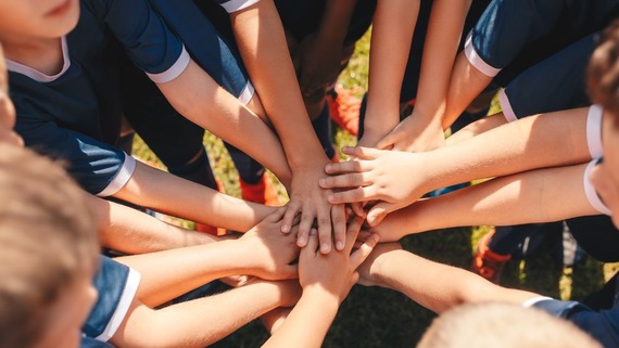 photo of a team of children putting their hands together in the centre of a circle
