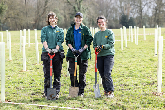 Three countryside rangers with spades smile at the camera