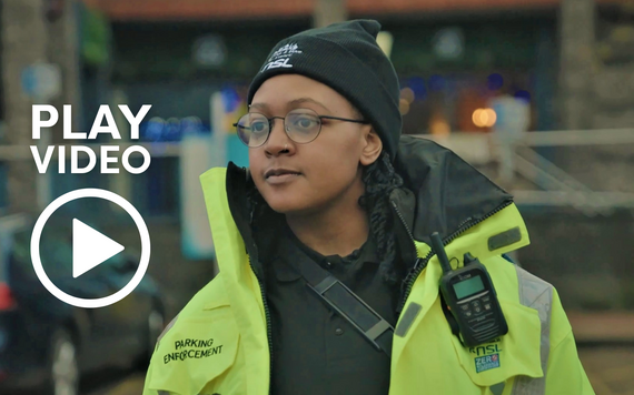 photo of a young woman parking warden on duty in high vis and a black beanie hat