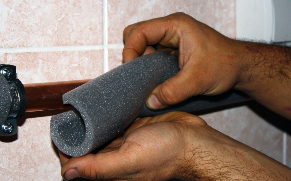 A person installs pipe insulation