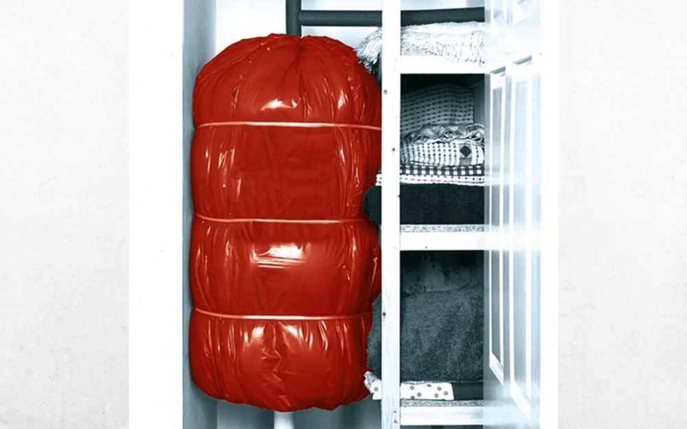 A hot water tank with red insulation pictured in a closet