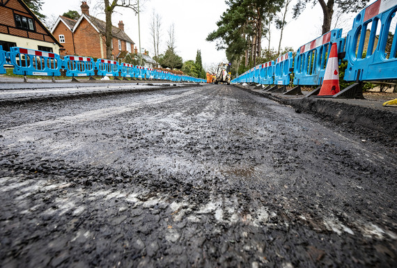 Close up of a new road during resurfacing, looking at the asphalt in detail with workers in background