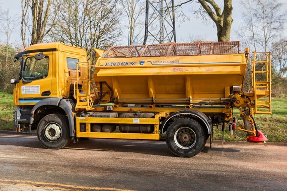 side view of a gritter on a country lane on a winter day