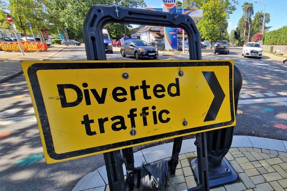 close-up of a "Diverted Traffic" sign with vehicles queuing on a junction in the background
