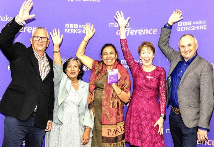 Five adults stand before a purple backdrop. One holds a purple award. BBC Radio Berkshire and “Make a Difference” logos are visible.