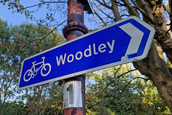an old signpost in Palmer Park pointing to Woodley with a logo of a cycle