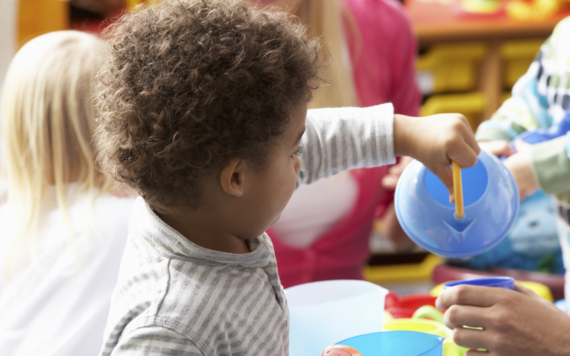 A young child tipping a plastic watering can