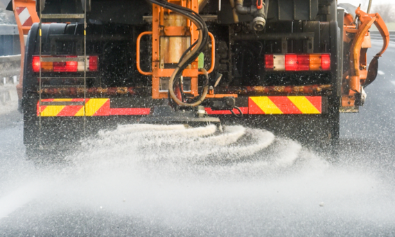 close up of salt being sprayed from the back of a gritter lorry on a dual carriageway