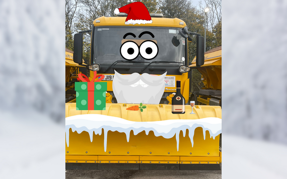 a gritter in a yard, mocked up with a giant Santa face and hat and a large gift on top of its snow plough