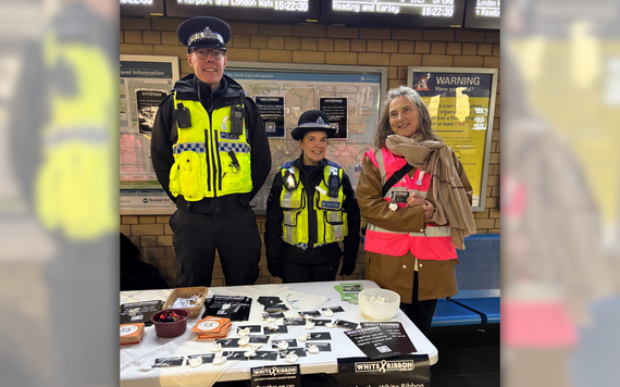 a male police officer and a female police officer alongside a volunteer handing out knitted white flowers for White Ribbon campaign