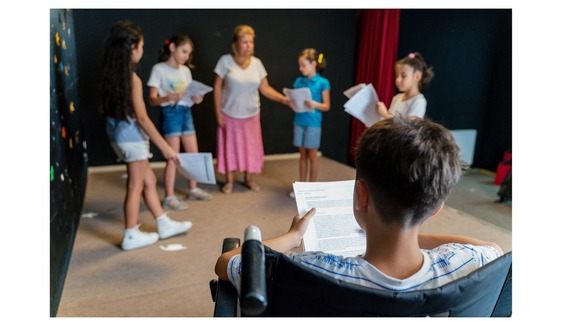A group of children holding scripts rehearsing a play