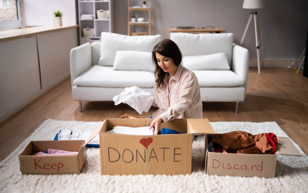 Woman sorting unwatend items into keep, donate and discard boxes