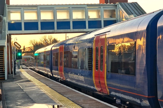 a train pulling away from Wokingham station on a green light just after sunrise in winter