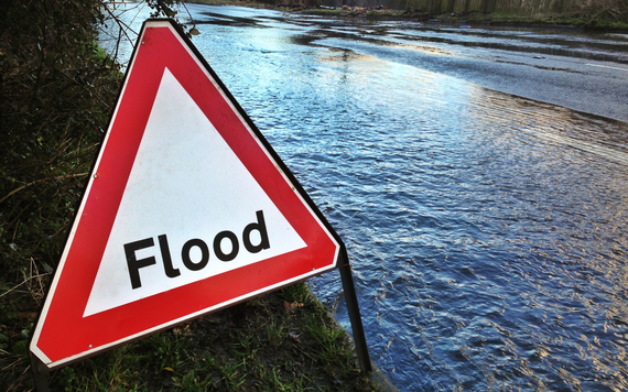library image of a temporary triangle sign with the word "flood" placed at the side of a flooded road