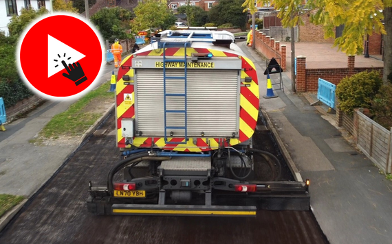 aerial view of a resurfacing lorry spreading new asphalt on a residential street, with a play button and finger clicking on it