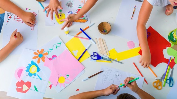 a table with craft materials, and children's hands doing crafts