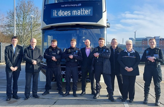a group of police officers and people in suits standing in front of a bus, with "it does matter" on the destination board