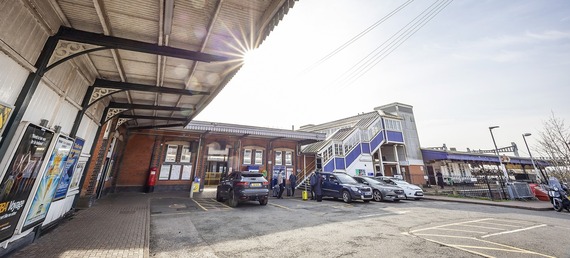 ultra wide shot of the old canopies at the entrance to Twyford station, with cars parked outside and the sun rising above them