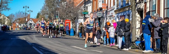 ultra wide shot of Wokingham half marathon, with large group of runners on a closed road in Wokingham town centre