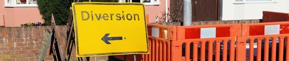 a sign saying "diversion" with an arrow in front of red closure barriers