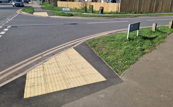 A new dropped kerb crossing with tactile paving across a side road that turns off a major road in Wokingham town