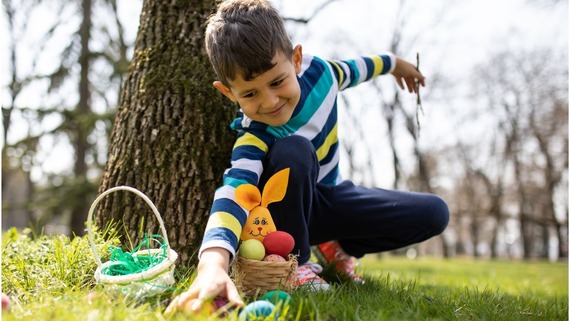child reaches for an easter egg  on an outdoor egg hunt 