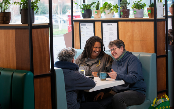 Three woman chatting and laughing drinking coffee