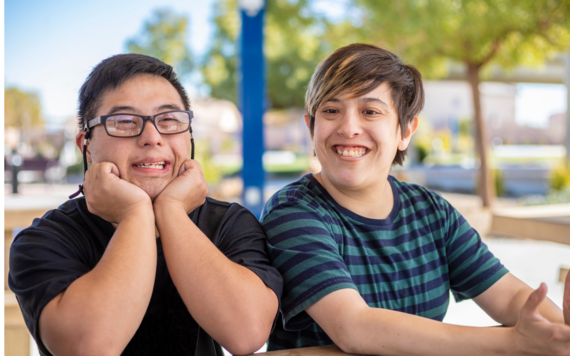 Two teenagers sat at a picnic bench, smiling