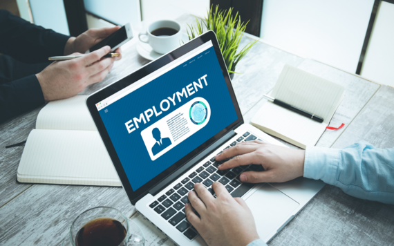 A person is using a computer. The image on the screen says 'Employment'
