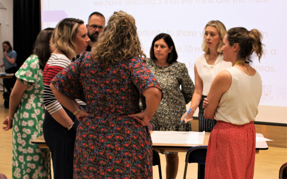 Group stand and discuss engagement issue around a table