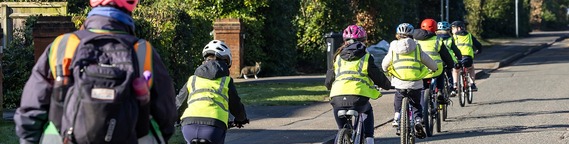 rear view of children in high-vis vests cycling in a group