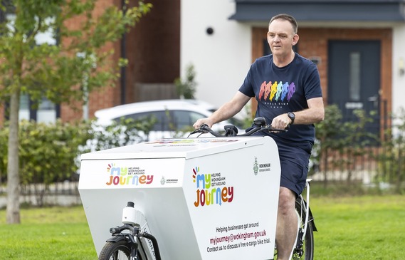 a man riding an electric bike with a large cargo box mounted over the front wheel