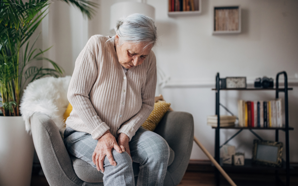 Woman sat on sofa with knee pain