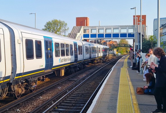 the side of a train that has pulled into Wokingham station, with passengers waiting on the opposite platform