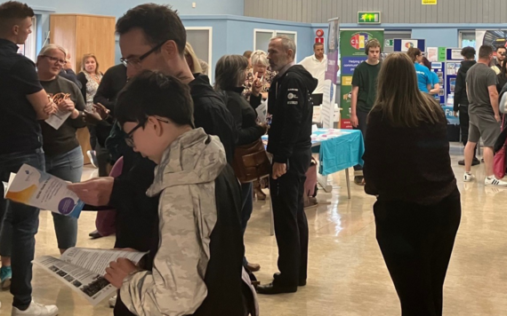 A group of people visiting stalls in a hall